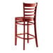 A Lancaster Table & Seating mahogany wood bar stool with a ladder back and wood seat.