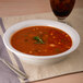 A Libbey Rigel Constellation Lunar bowl of soup with a sprig of rosemary and a silver spoon.