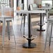 A Lancaster Table & Seating black cast iron bar height table base with a metal foot ring.