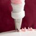 A pastry bag with an Ateco drop flower piping tip being used to decorate a cake.