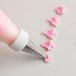 Pink flowers piped from an Ateco leaf pastry tip using a pastry bag with pink frosting.