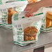 A hand holding a plastic bag of Fresh Flavor fried chicken.