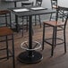 A Lancaster Table & Seating black cast iron bar height table base with a foot ring.