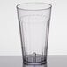 A Carlisle clear plastic tumbler with a clear rim on a table.