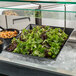A black G.E.T. Enterprises Bugambilia resin-coated aluminum bowl of pasta and salad on a counter.