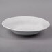 A Libbey Lunar Bright white porcelain soup bowl with a rim on a gray surface.