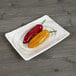 A red and yellow peppers on a white Elite Global Solutions rectangular melamine plate.