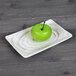 An Elite Global Solutions rectangular taupe melamine plate with a green apple on it.
