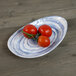 An Elite Global Solutions oval melamine plate with tomatoes on it.