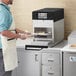 A man putting food into an ACP XpressChef 3i countertop oven.