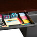 A Hirsh Industries charcoal and mahogany left corner pedestal desk with a drawer full of office supplies.