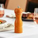 An Acopa matte brown wooden pepper mill on a table.