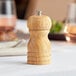 An Acopa wooden pepper mill on a table.