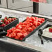 A G.E.T. Enterprises Bugambilia black metal rectangular platter with watermelon cubes and strawberries.