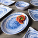 A close up of a rectangular navy melamine plate with blood oranges on a wood table.
