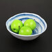 A navy oval melamine bowl filled with green apples.