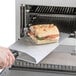 A sandwich being cut on a metal plate.