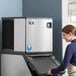 A woman standing next to a Manitowoc air cooled ice machine.