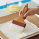 A hand using a Carlisle Sparta Spectrum pastry brush to baste a piece of dough.