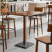 A Lancaster Table & Seating live edge bar height table with wooden stools.