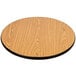 A Lancaster Table & Seating round wooden table top with walnut finish on a table with a cross cast iron base.