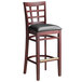 A Lancaster Table & Seating mahogany wood bar stool with a black vinyl seat.