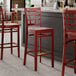 A Lancaster Table & Seating mahogany wood bar stool with a mahogany wood seat.