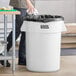 A man standing next to a white Lavex round commercial trash can.