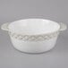 A close up of a Tuxton white round casserole dish with a diamond pattern on the band.