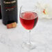 A Libbey Citation wine glass filled with red wine next to a bottle of wine on a table.