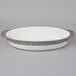 A white oval Tuxton china casserole dish with a silver and gray rim.