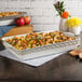 A white Tuxton rectangular casserole dish with food on a table.