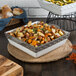 A white square Tuxton casserole dish filled with potatoes, zucchini, and squash.