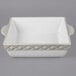 A white square ceramic casserole dish with handles.