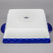 A white square Tuxton casserole dish with a cobalt blue band.