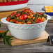 A Tuxton bright white round casserole dish filled with vegetables and corn.