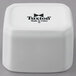 A white square Tuxton china cube with black text.