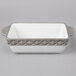 A white rectangular Tuxton casserole dish with a black truffle band.