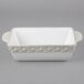 A white rectangular Tuxton casserole dish with a grey diamond patterned border.