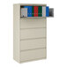 A five-drawer putty-colored lateral file cabinet with a roll-out binder storage shelf containing several binders.