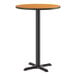 A round bar-height table with a reversible walnut or oak top and a black cast iron base.