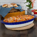 A Tuxton cobalt and white china casserole dish with pasta, meatballs, and cheese.