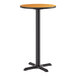 A round bar-height table with a wood-finish top and a black cast iron base.