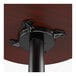A close-up view of the underside of a round wooden bar-height table attached to a black cast iron base.