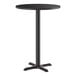 A round, black bar-height table with a single central pedestal and a four-pronged cast iron base.