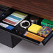 A desk drawer with stationery and pens, including a spiral bound notebook.