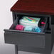 A charcoal and mahogany right corner pedestal desk with a drawer open to reveal stationery inside.