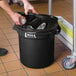 A person putting foil in a black trash can lid.
