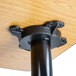 A Lancaster Table & Seating black metal cross base plate on a wood table.