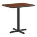 A rectangular standard height table with a reversible walnut and oak top and a black cast iron base.